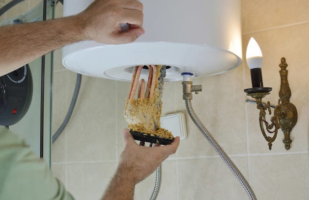 Technician removing mineral buildup from a water heater in Holly Springs