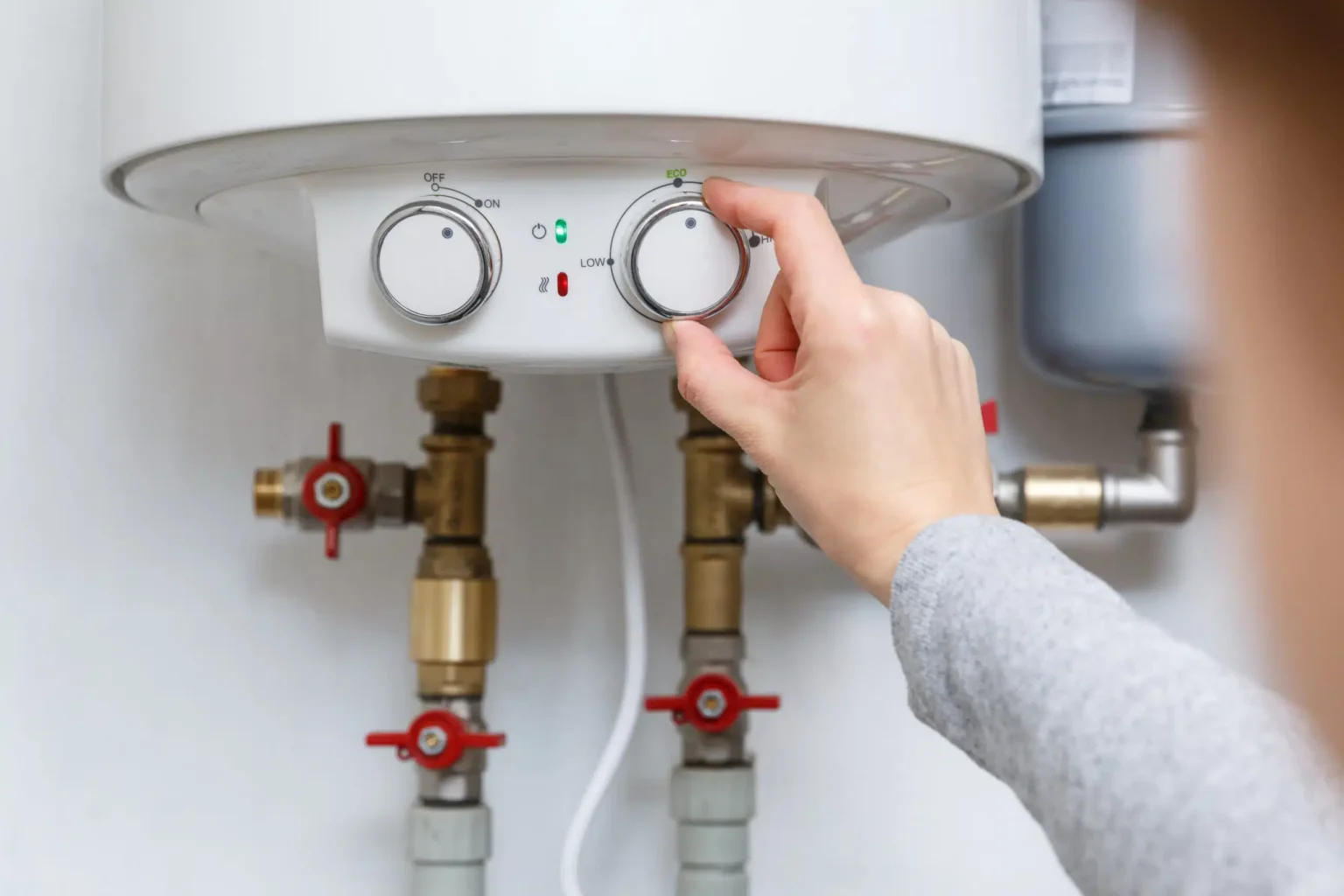 Homeowner adjusting the temperature controls on a water heater in Holly Springs